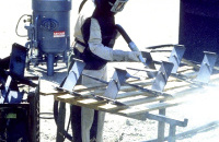 6.6. Sandstrahler mit mit Sandstrahl-Overall sowie Sandstrahl-Schutzhandschuhe im Hintegrund Sandstrahl-Druckstrahlgerät